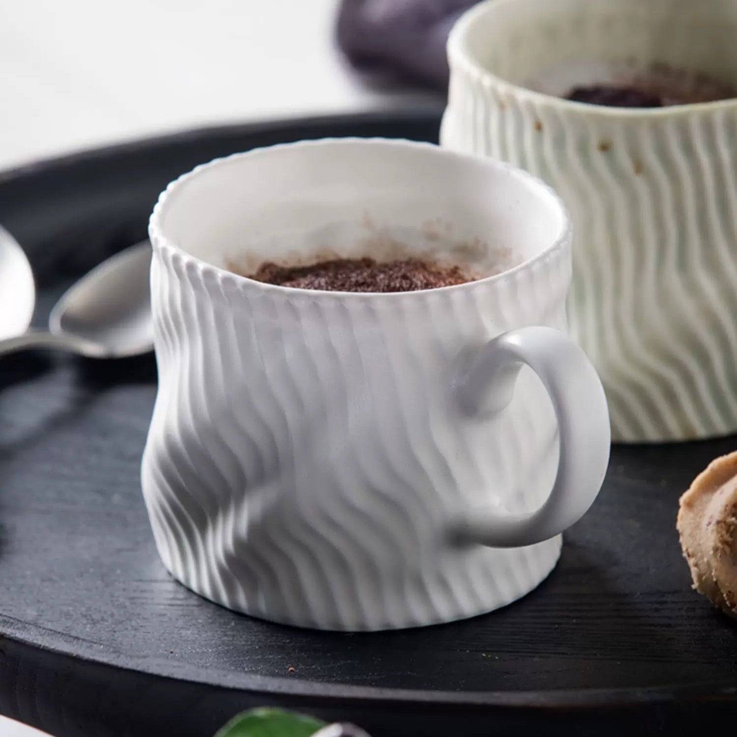 White textured mug on a dark surface with another mug in the background