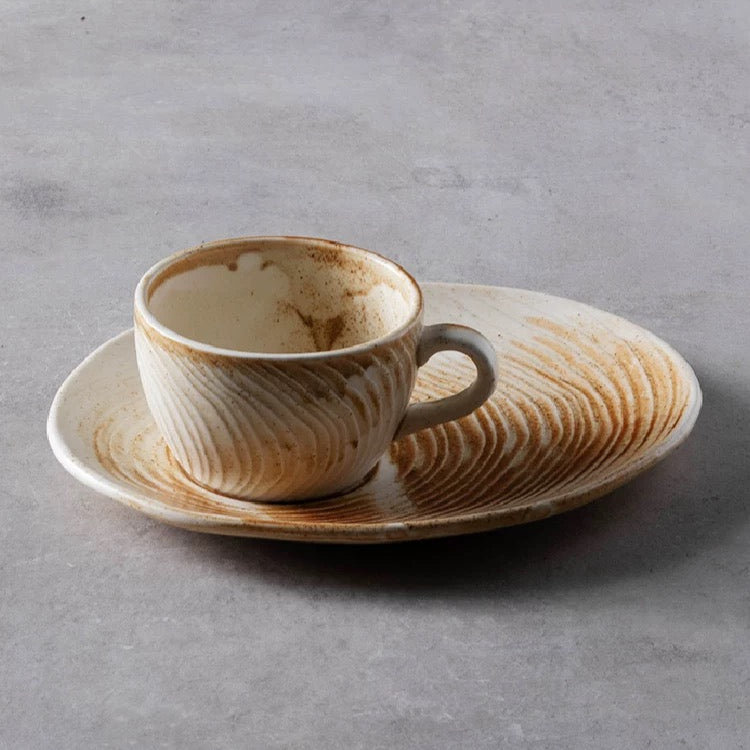 Ceramic cup and saucer set with marbled design on a gray background, featuring the brand 'Alaniz'.