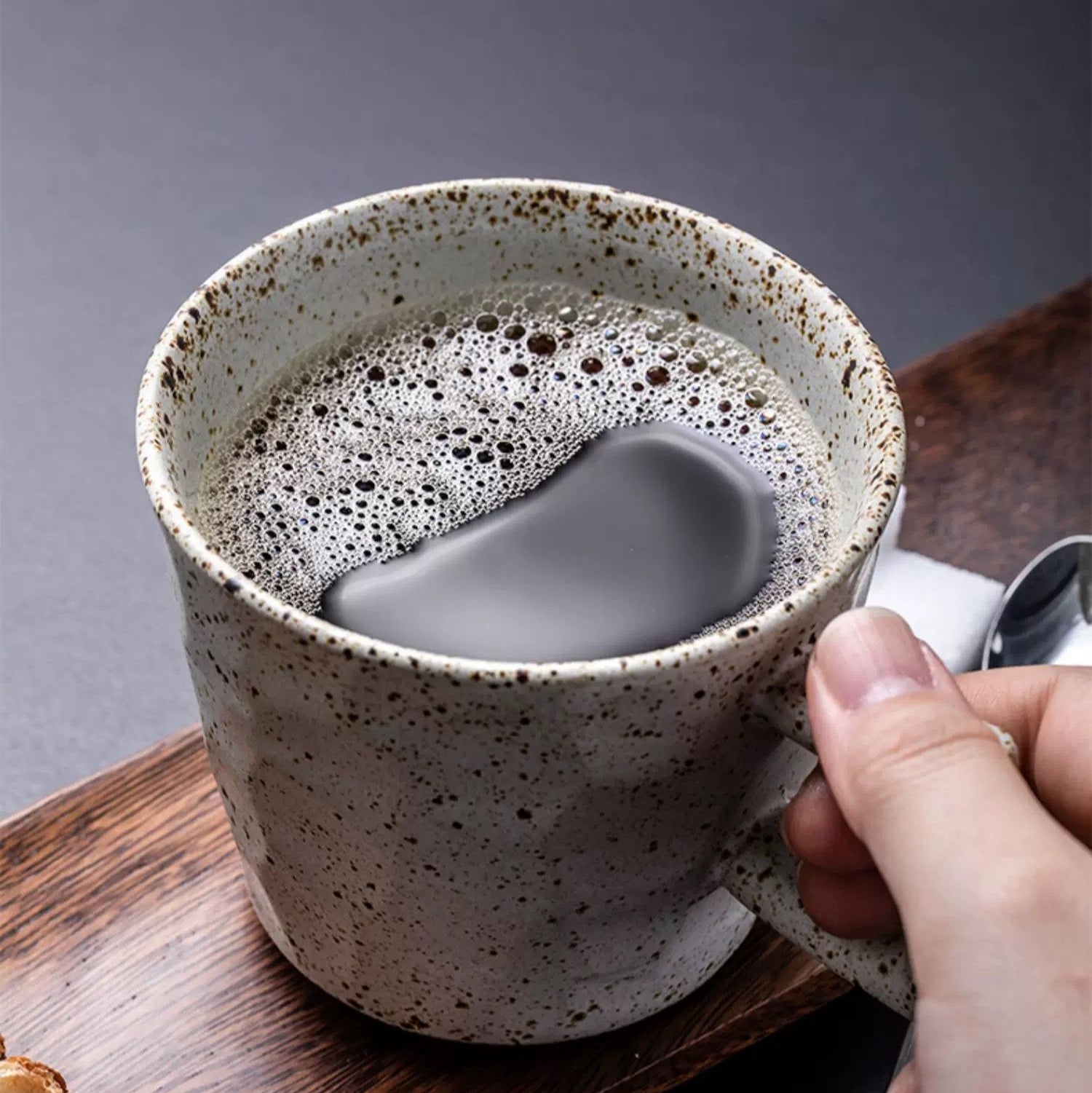Rust series mug with a hand holding it, filled with a beverage on a wooden surface.