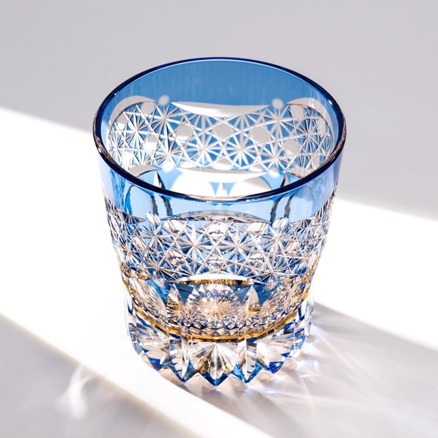 Blue crystal glass with intricate patterns on a white surface