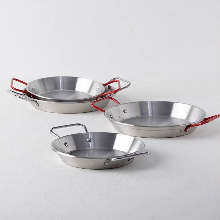 Three metallic frying pans with red handles on a light gray background, featuring the ALANIZ brand.