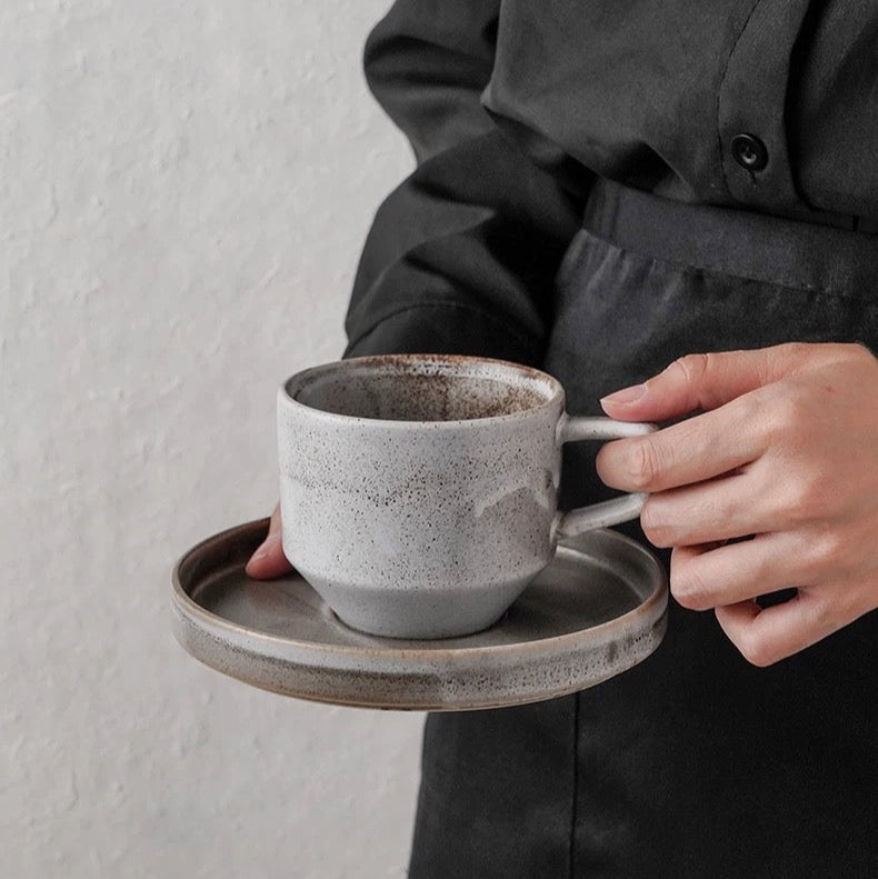 Person holding a ceramic cup and saucer