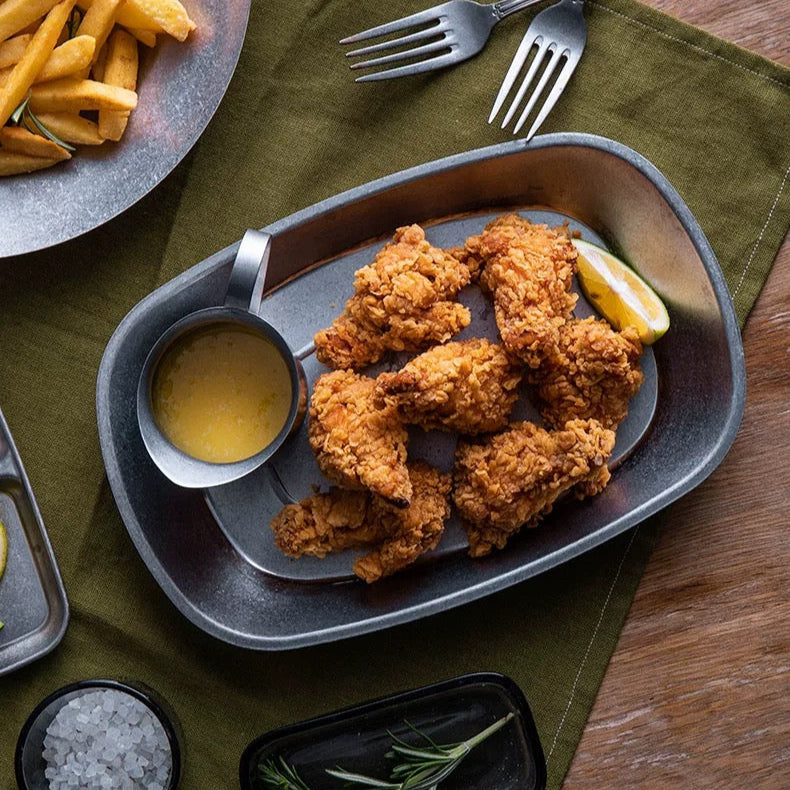 Fried chicken with fries and dipping sauce in a Stainless Steel plate on a wooden table 