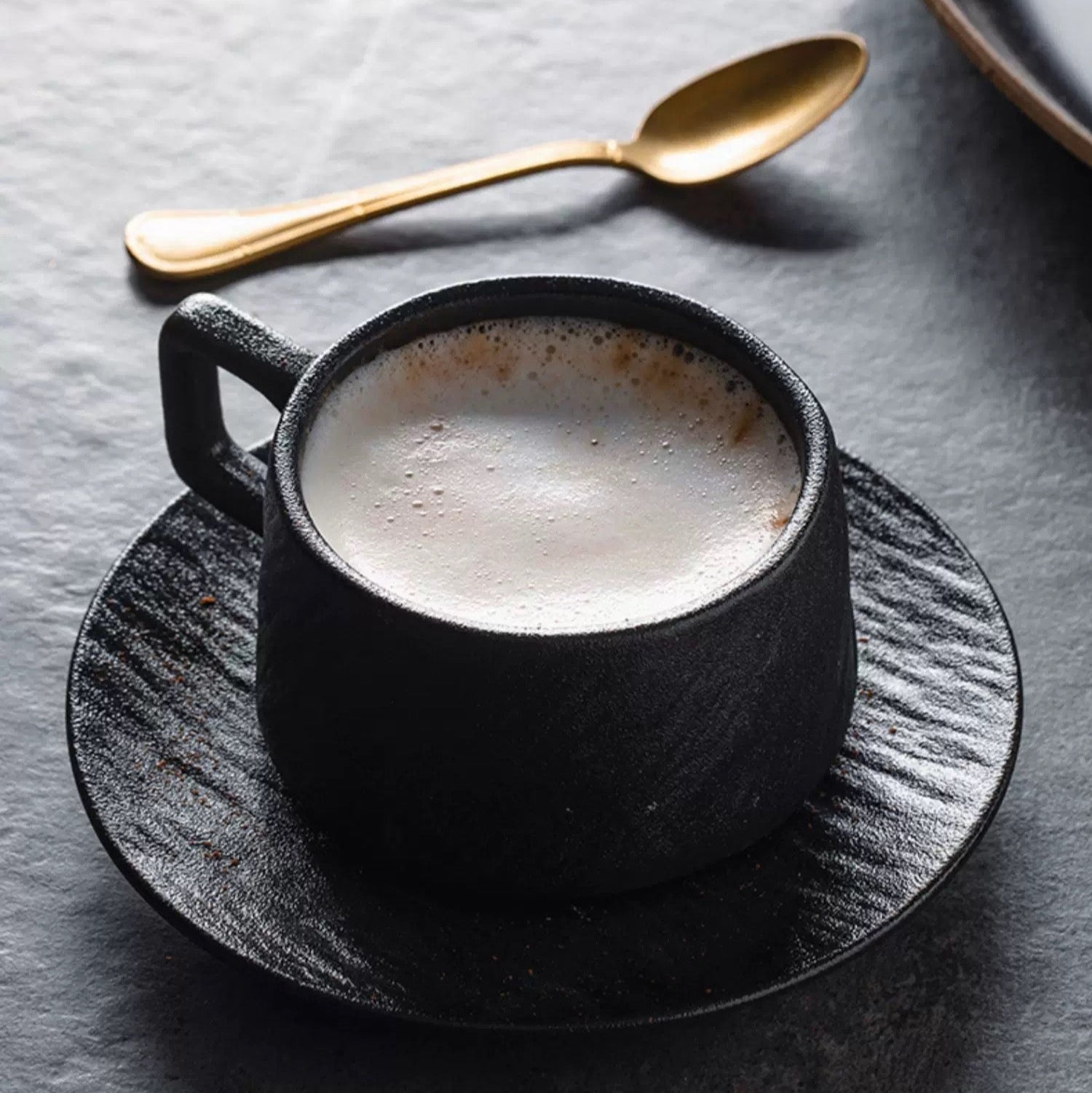 Coffee set with black cup and saucer on a dark surface,