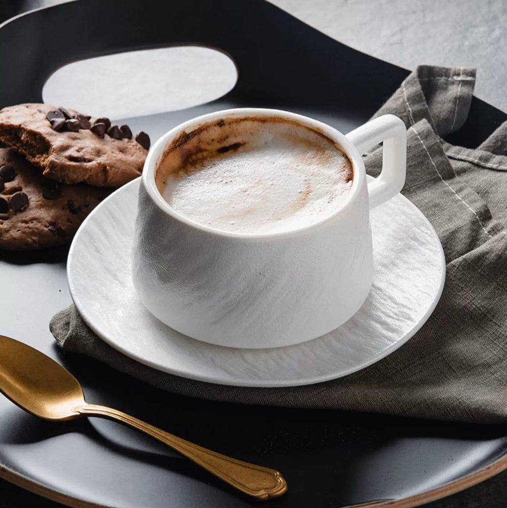 White ceramic cup with coffee and cookies on a dark surface